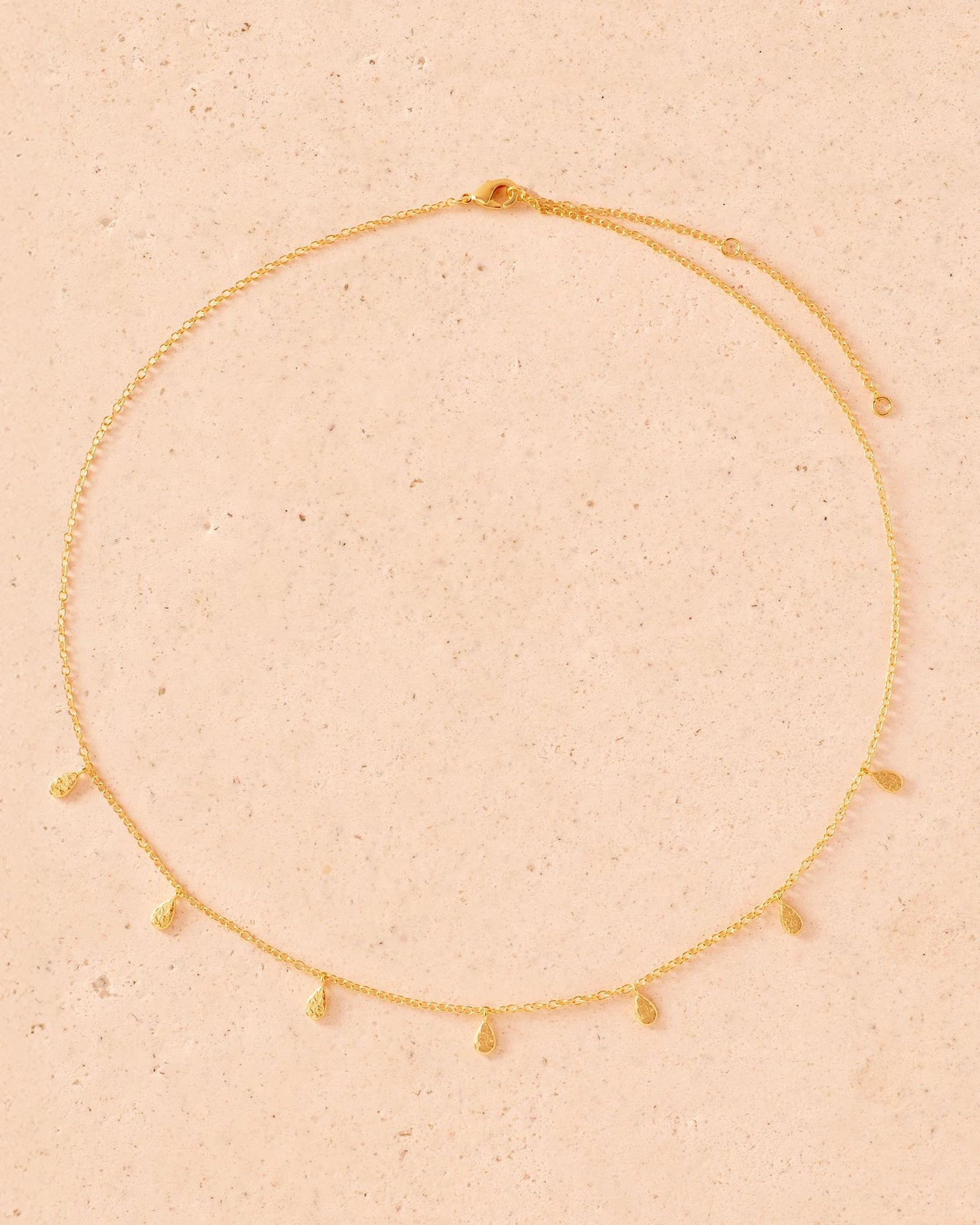 Gold Marta Necklace with delicate chain and multiple textured teardrop charms.
