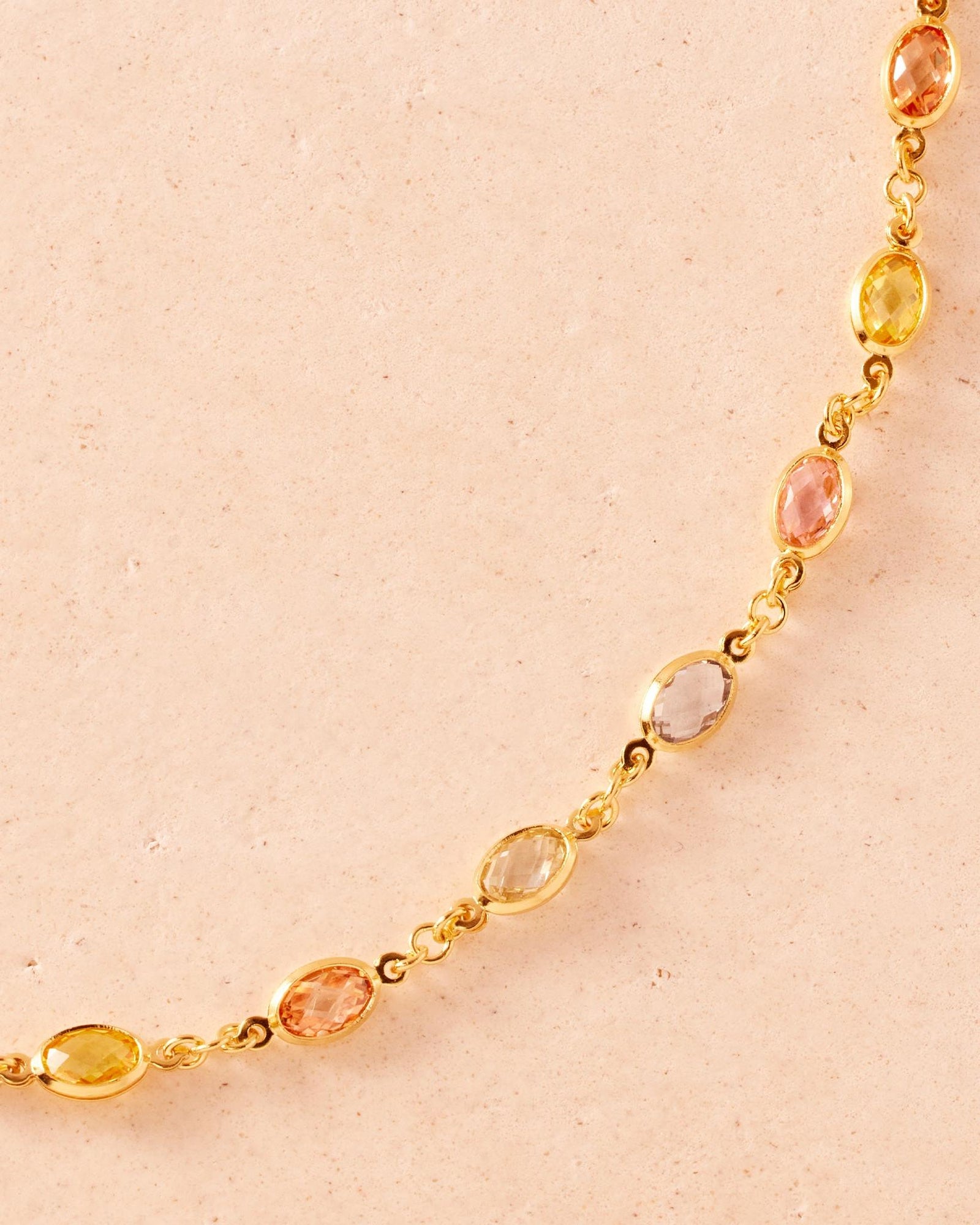 Gold chain necklace with alternating oval multicolored stones in yellow, pink, blue, orange, and green.