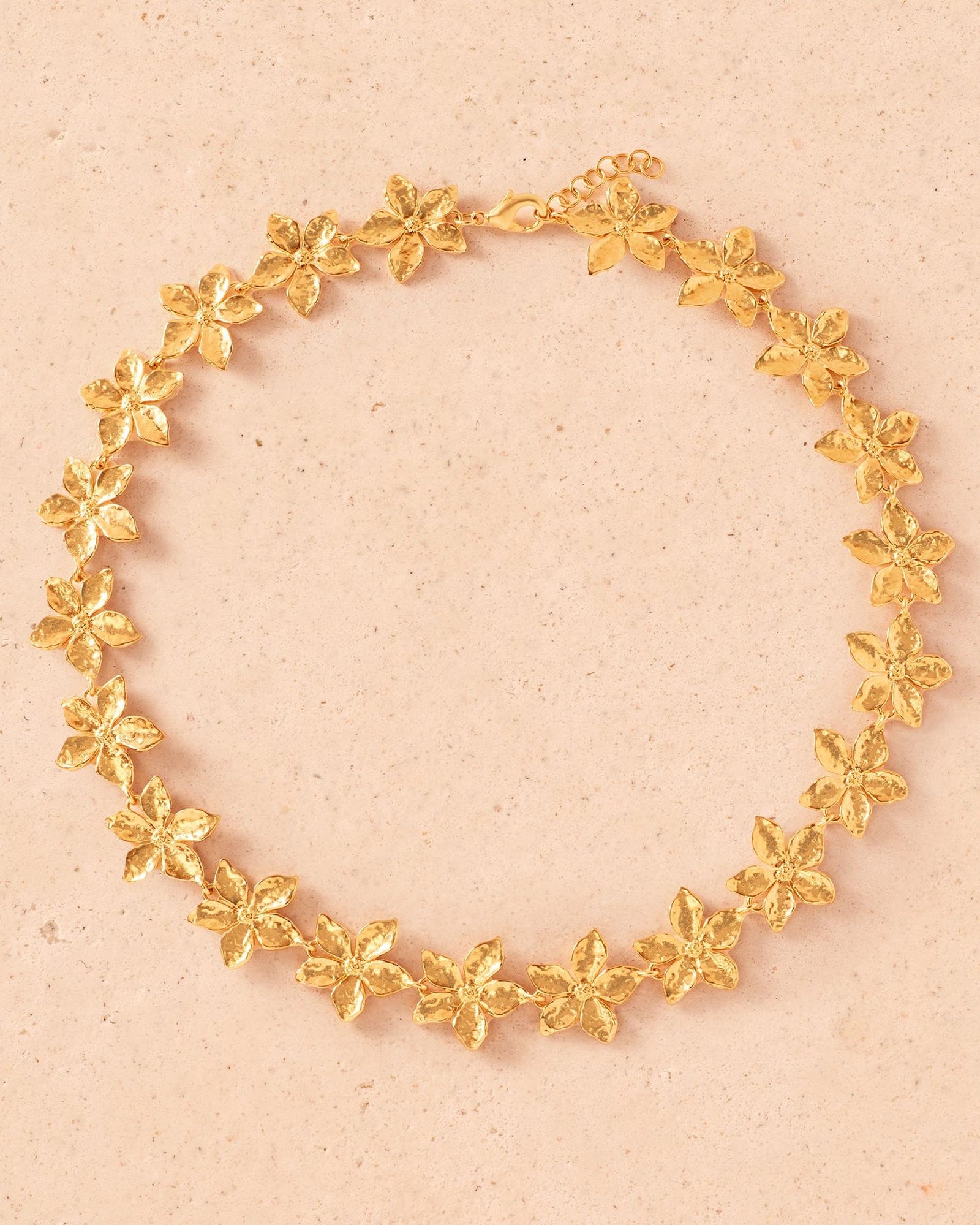 Thalla gold floral choker with hammered five-petal flowers, delicate details, and an adjustable clasp.