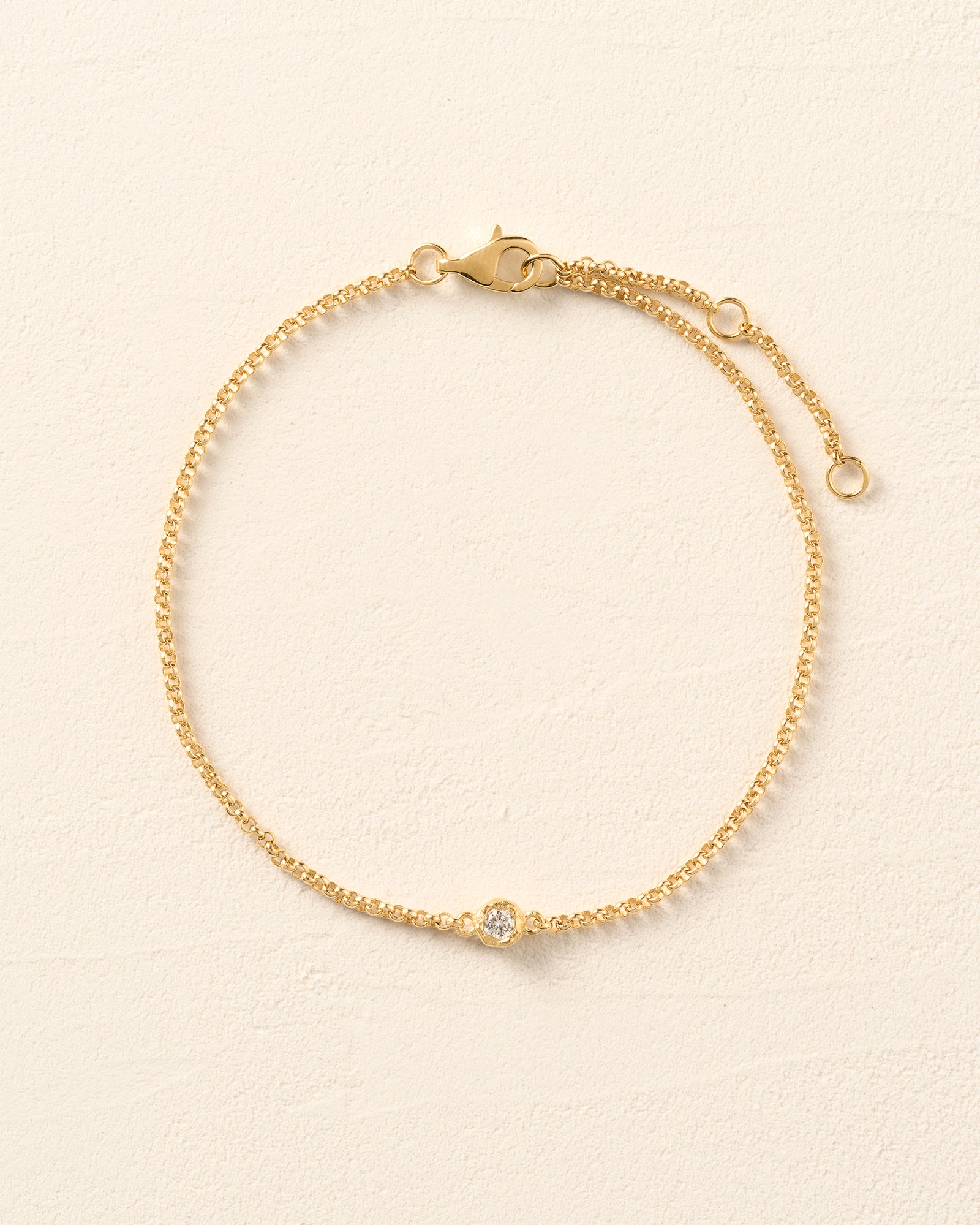 Ada Bracelet: Thin gold rolo chain with a single round lab-grown diamond in an irregular golden bezel.