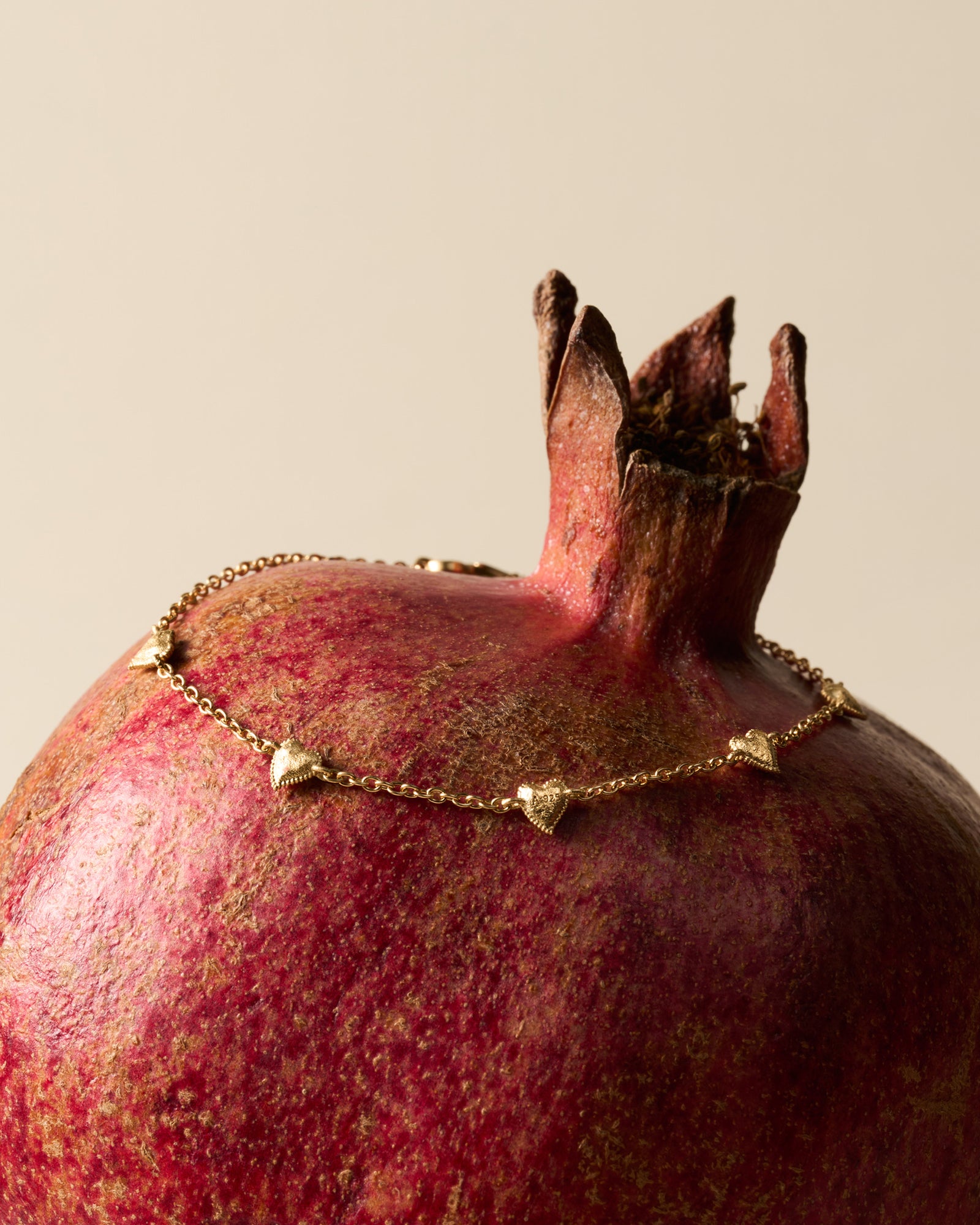 Amori Bracelet: Golden chain with small, hammered, domed heart charms on a pomegranate.