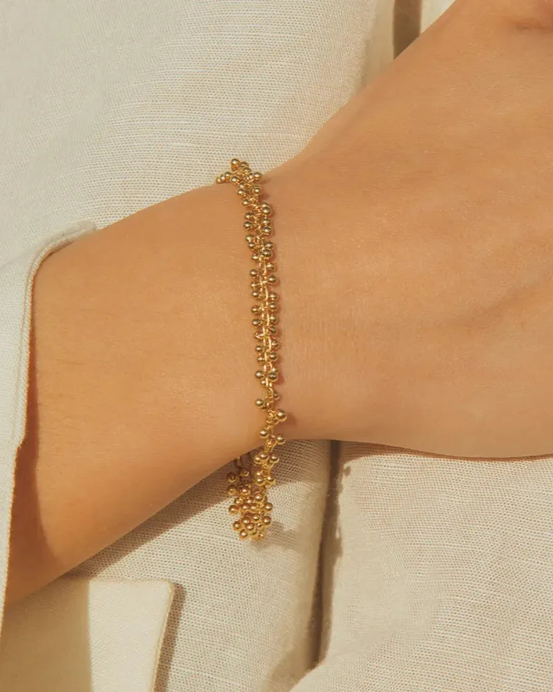 Achille gold beaded bracelet on a wrist, featuring a delicate, luminous design.