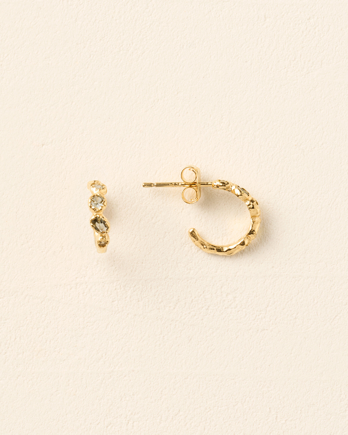 Gold hoop earrings with a textured finish, each hand-set with five small, blue-green celadon stones.