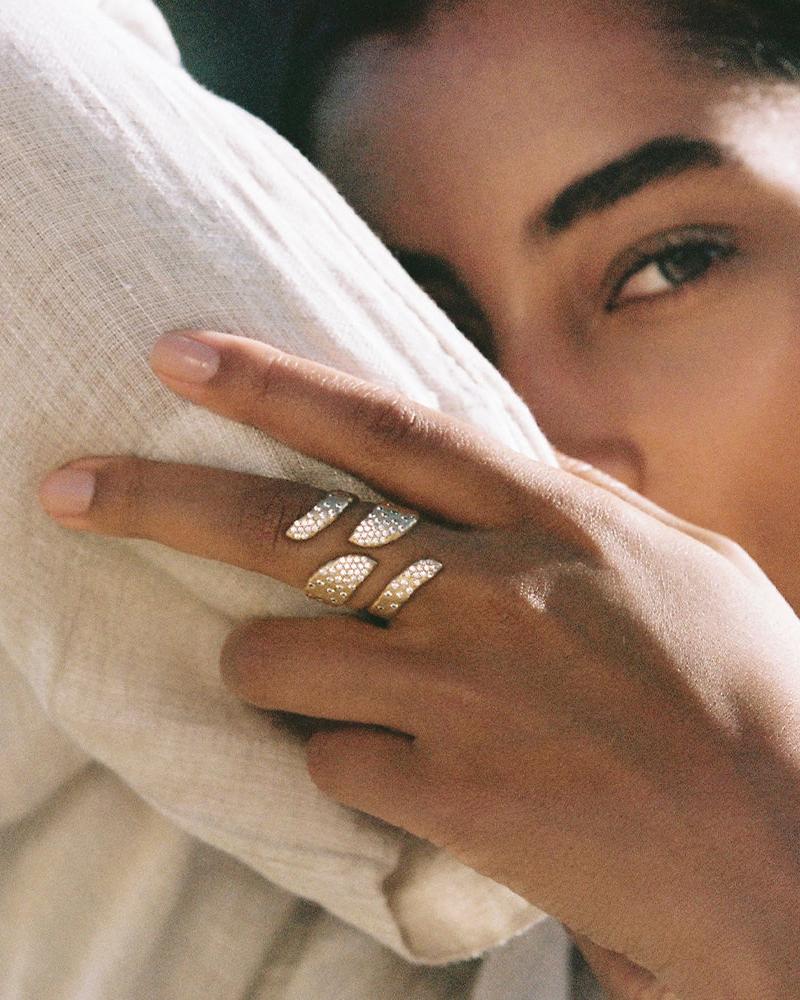 Rhéa open ring, gold-toned, with irregularly inlaid white stones, worn on a finger.