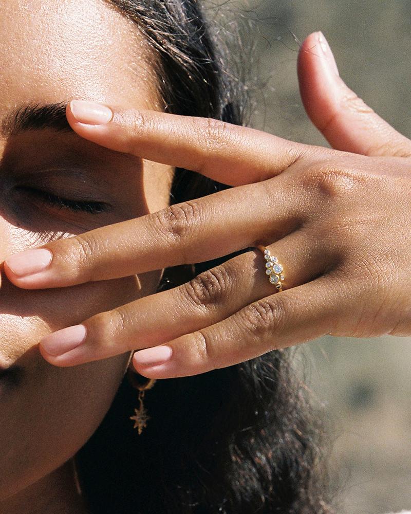 Gold Atys slim cluster ring with irregularly inlaid white stones on a hand.