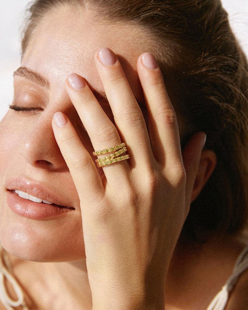 Amalia Green Ring: Three stacked gold bands with green stones on a woman's finger.