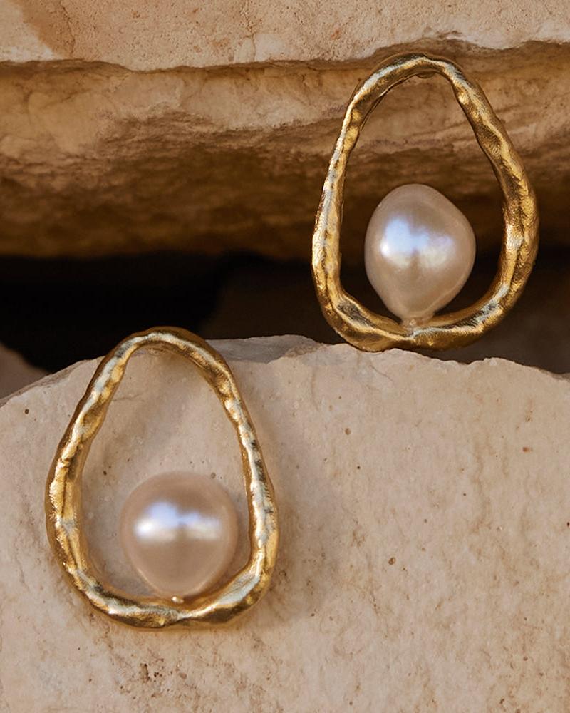 Ostuni mother-of-pearl pendant earrings with textured gold halo, displayed on natural stone.