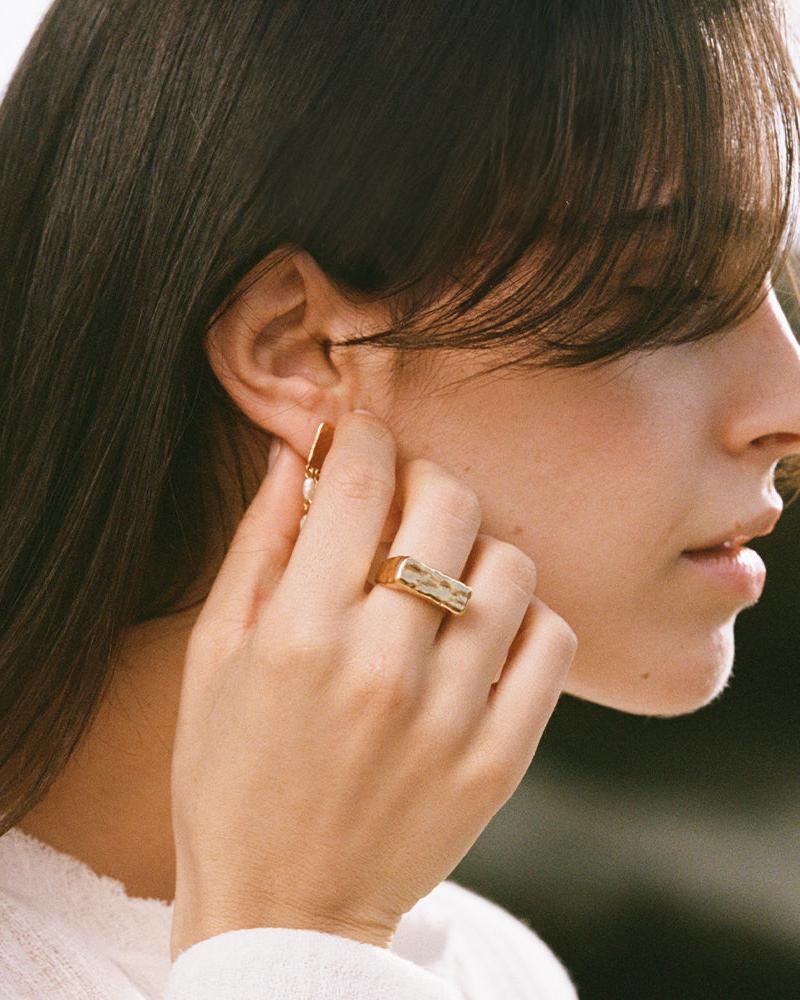 Gold hammered rectangle signet ring on a woman's hand, showcasing its chunky, rough, and bold design.