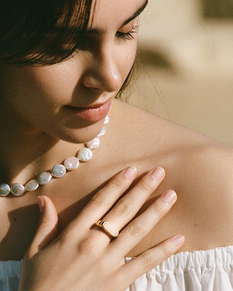 Losna gold signet ring with an oval iridescent moonstone on a woman's finger.