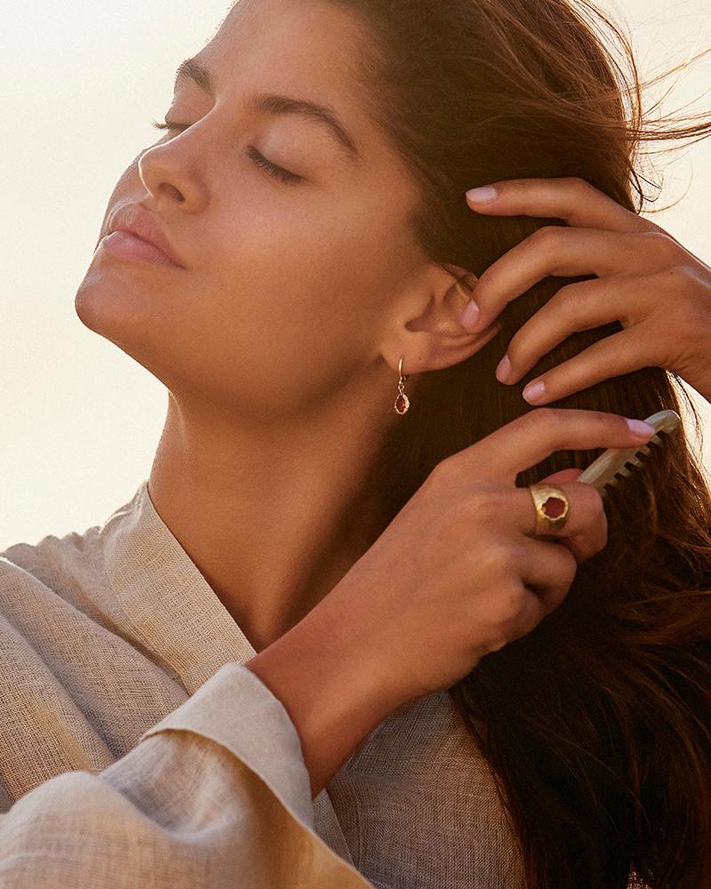 Lysia rosewood drop earrings on small gold hoops, worn by a woman with a matching gold ring.