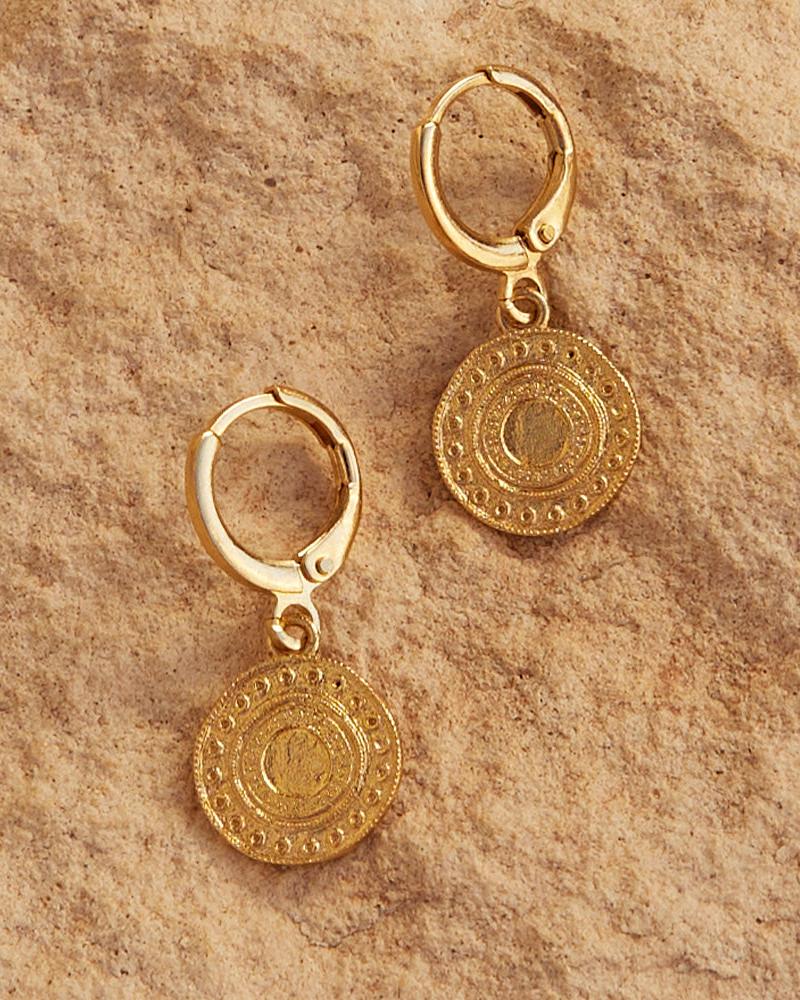 Alba gold-plated earrings with intricate Persian-inspired coin-like charms on a textured background.