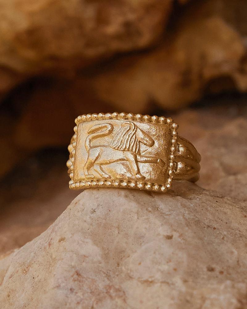 Gold Arielle ring with a rectangular face featuring an embossed lion and beaded border.