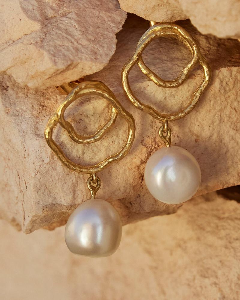 Gold Célaphine earrings with organic, wavy shapes and dangling lustrous white pearls.