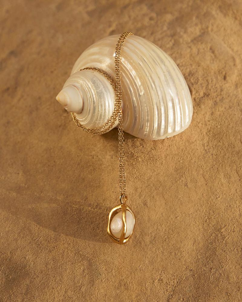 Daria Halskette mit Süßwasserperle in einem organischen, unregelmäßigen, goldfarbenen Käfig-Anhänger an einer zarten, goldfarbenen Kette.
