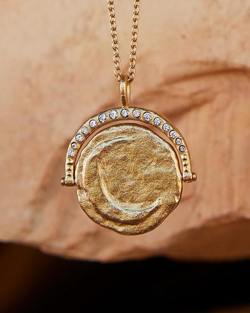 Gold Sirius rotating pendant necklace with textured sun design and inlaid gems.