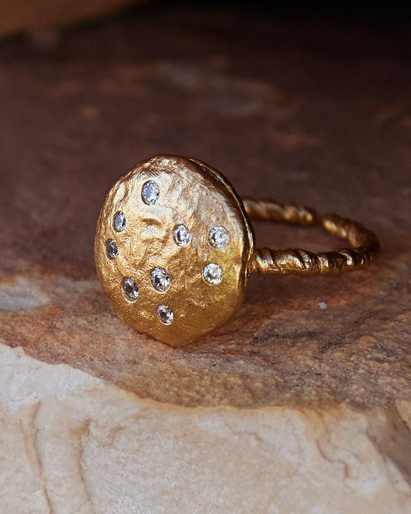 Gold Lattea ring with a twisted band and rotating centerpiece of inlaid white stones.