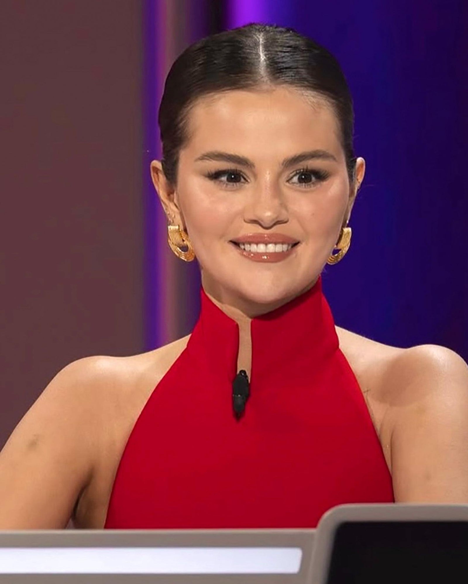 Selena Gomez wearing Giulia chunky gold ridged dangling hoop earrings with a red high-neck dress.