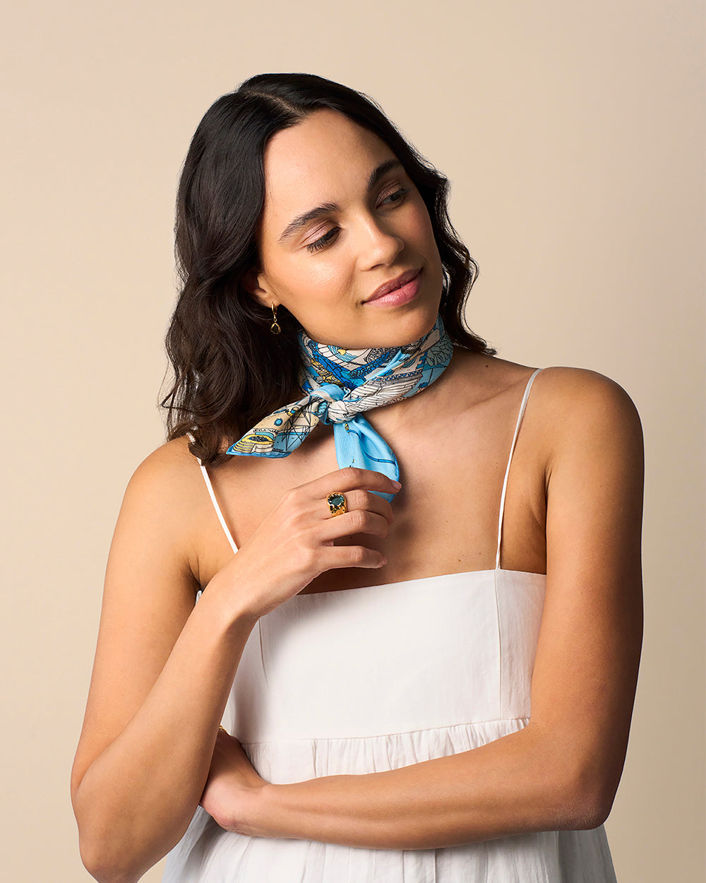 Woman wearing Atlantis Silk Scarf with blue, white, and gold Mediterranean-inspired design, paired with a white dress.