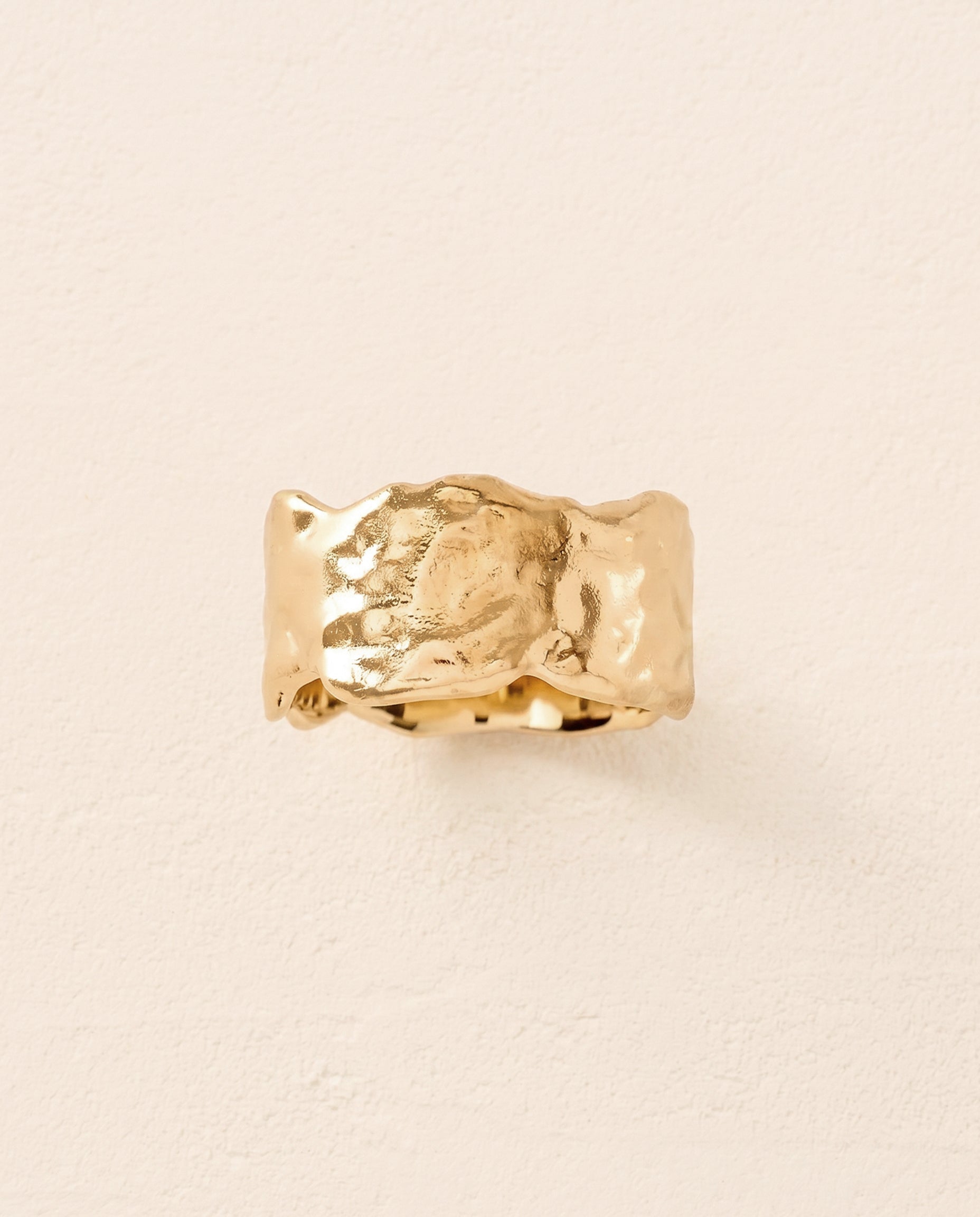Anello a fascia larga Alphée dorato dalle linee organiche fluide e dalla texture martellata.