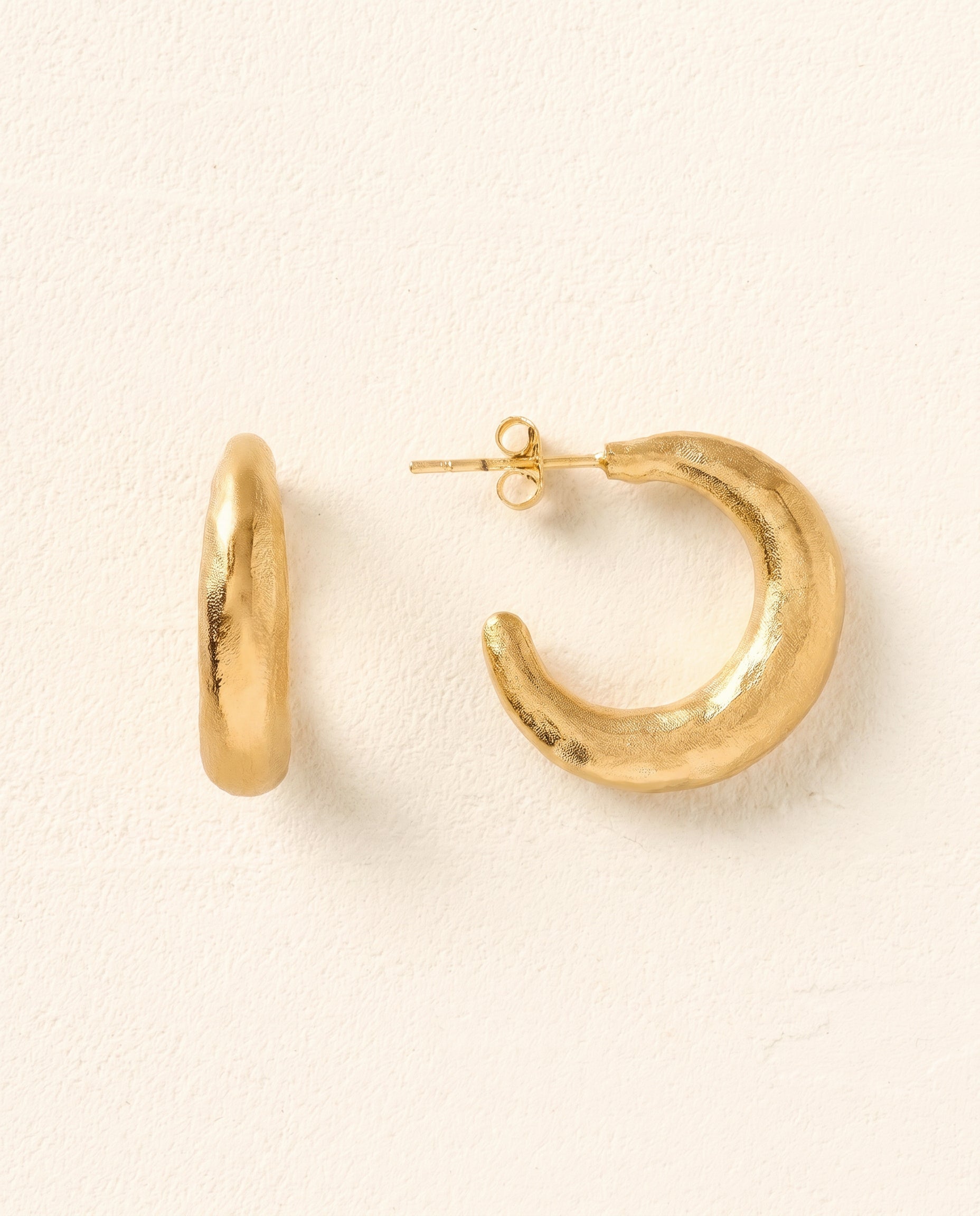 Gold Aura open hoop earrings with a hammered, imperfect finish.