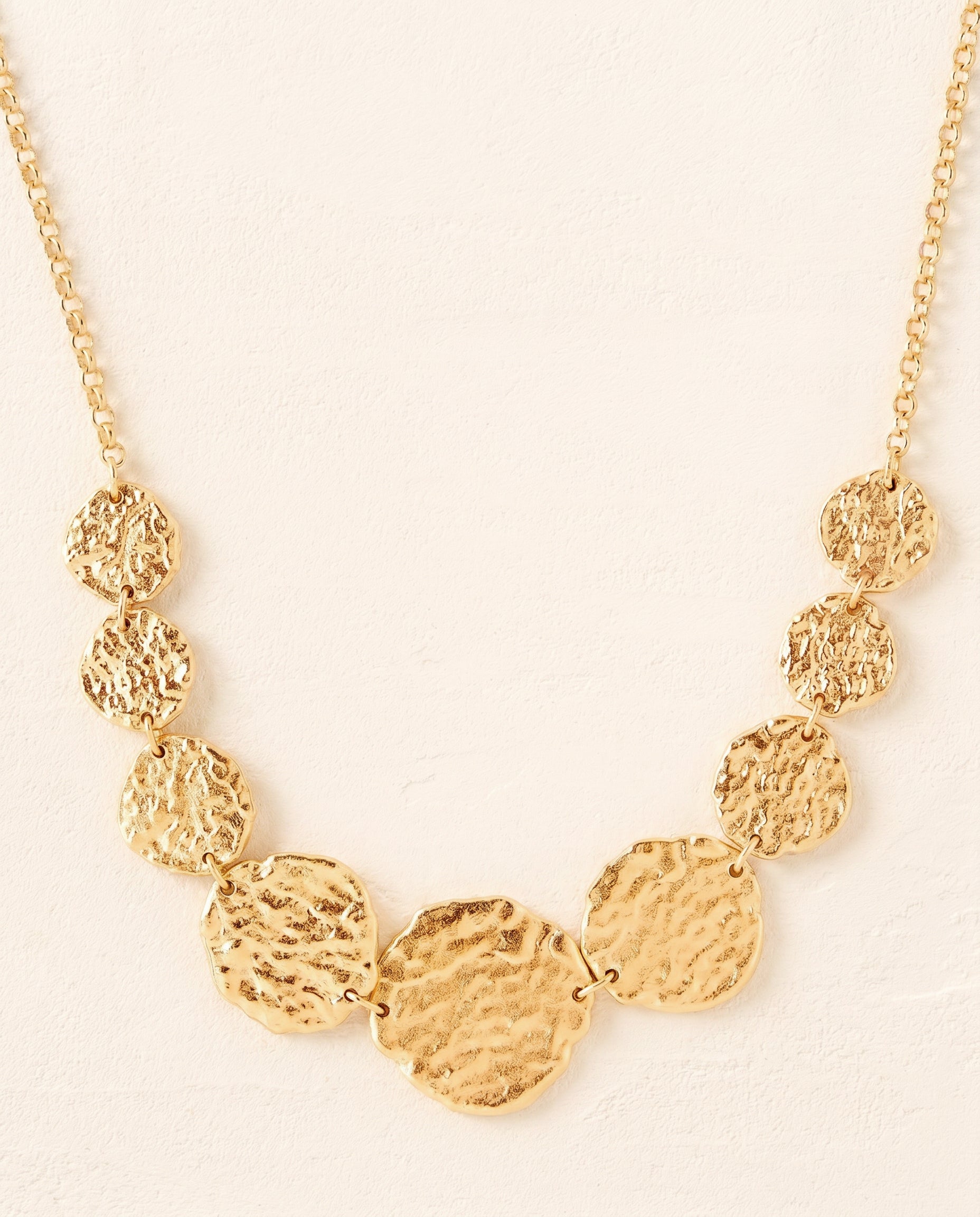 Graduated gold Cassia necklace with 9 hammered coin-like discs on a delicate chain.