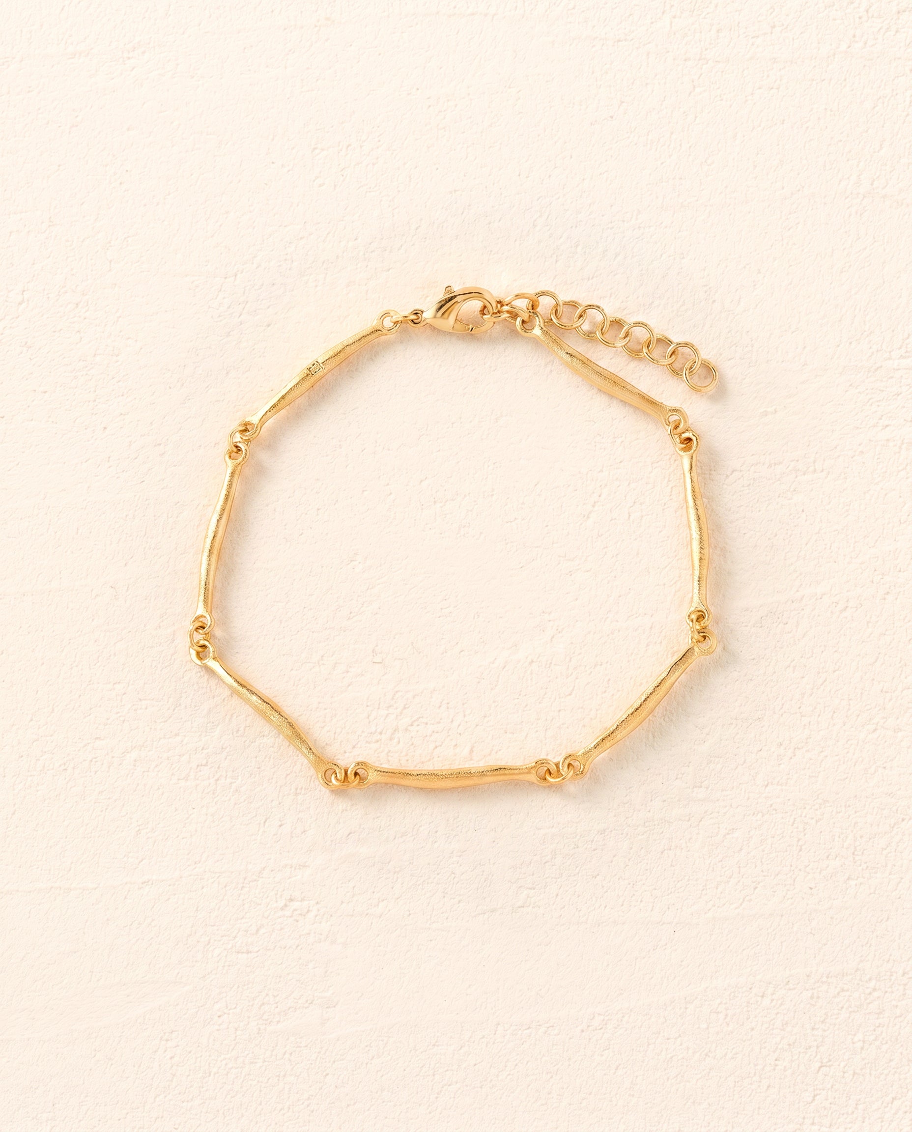 Enea slim gold bracelet with hammered, irregular bar-shaped links and an adjustable chain.