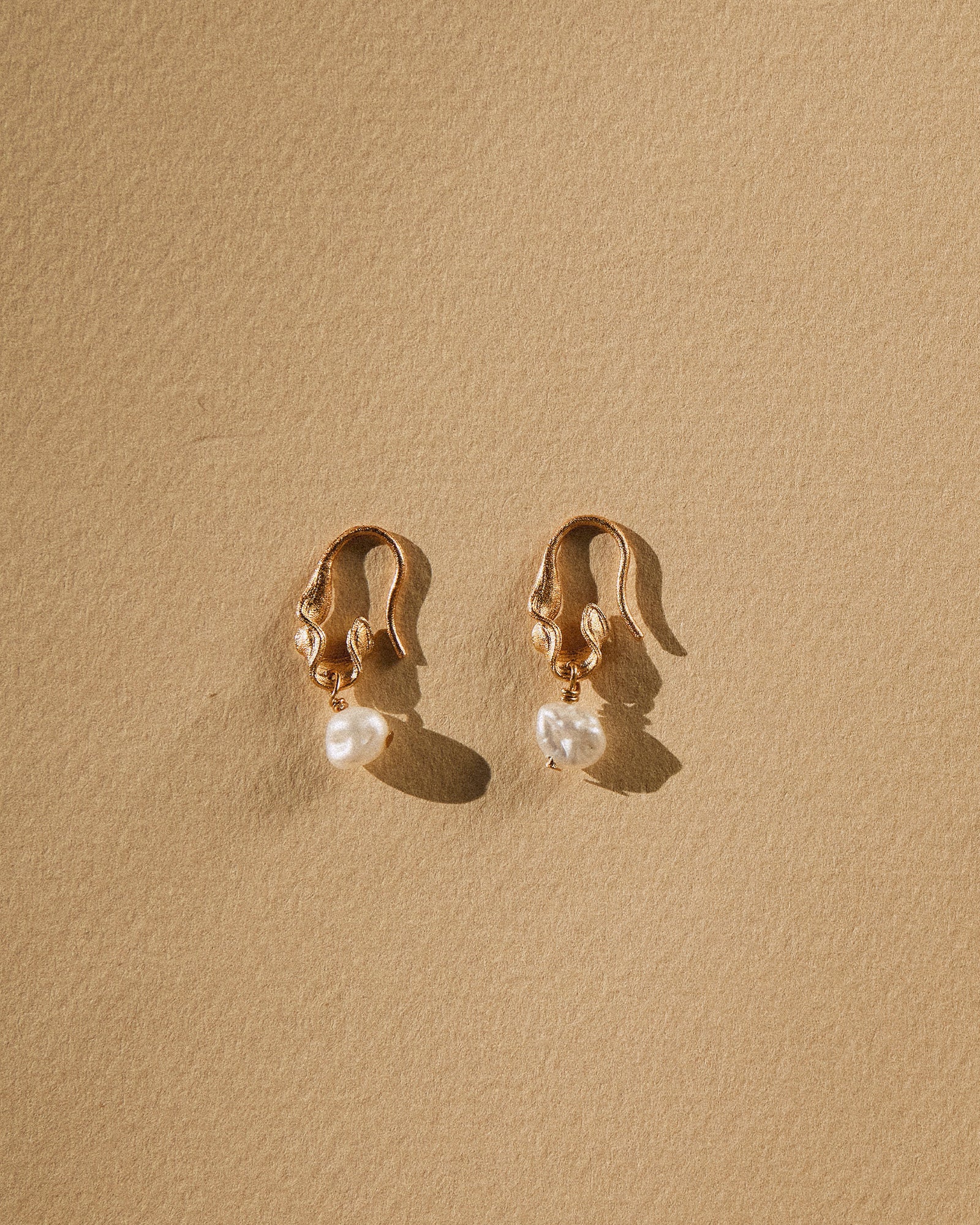 Gold twisted open hoop Phaedra earrings with single freshwater pearl pendants.