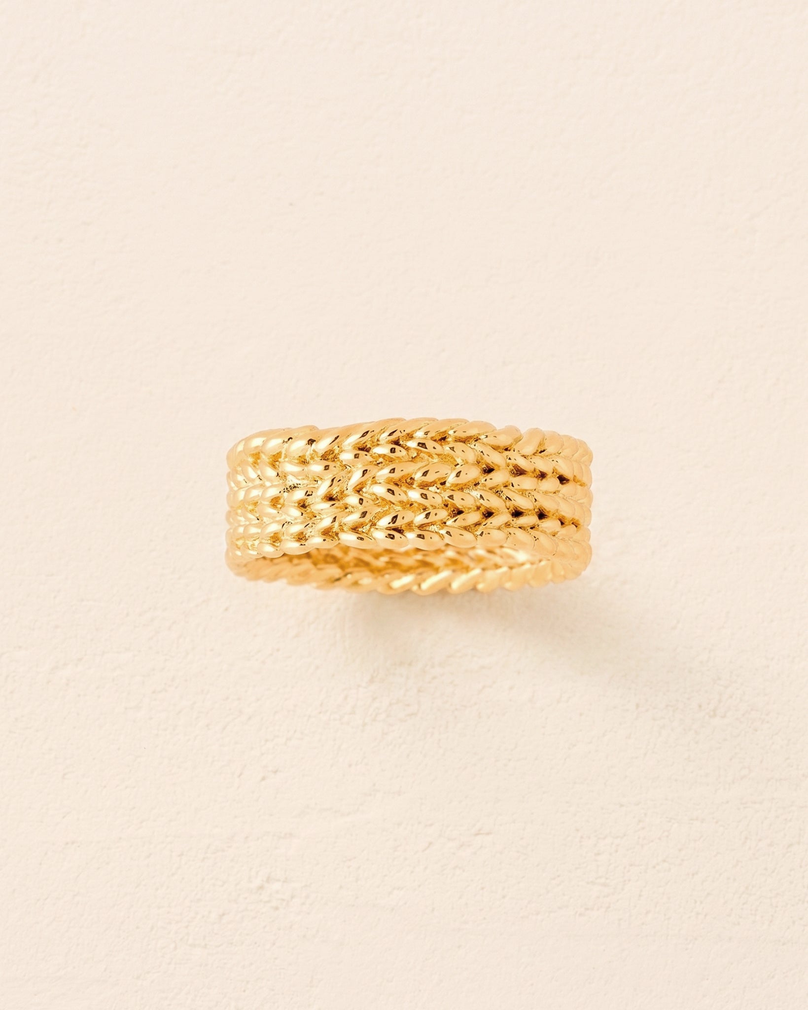 Gold Kotsi ring with a wide band and textured, asymmetrical braided rope design.